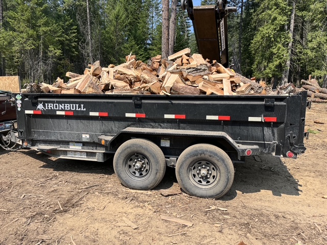 Tandem axle dump trailer loaded with split firewood in the woods