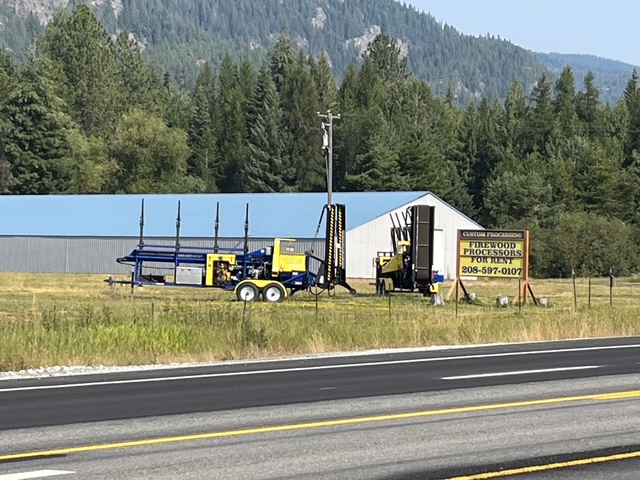 Firewood processors parked at the yard beside the highway sign advertising rentals
