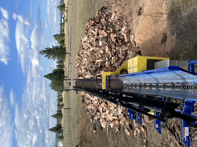 Looking down the processor conveyor at the firewood pile it built in a pasture
