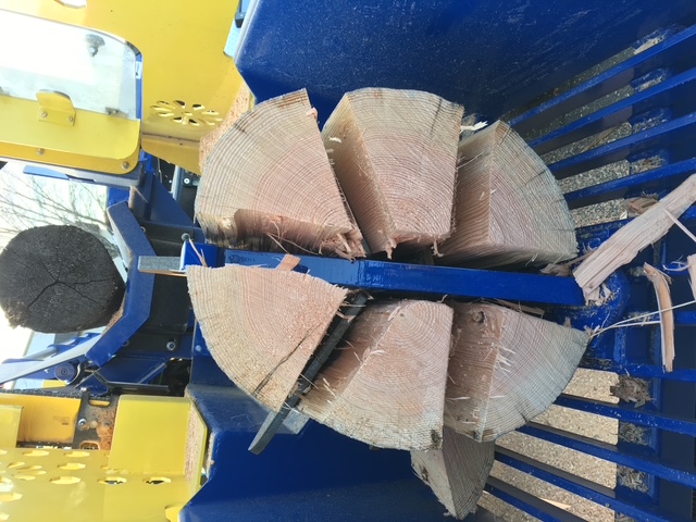 A log round split into six pieces by the splitting wedge inside the machine
